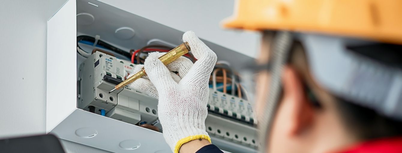 An electrician is working on the electrical components of a residential house.