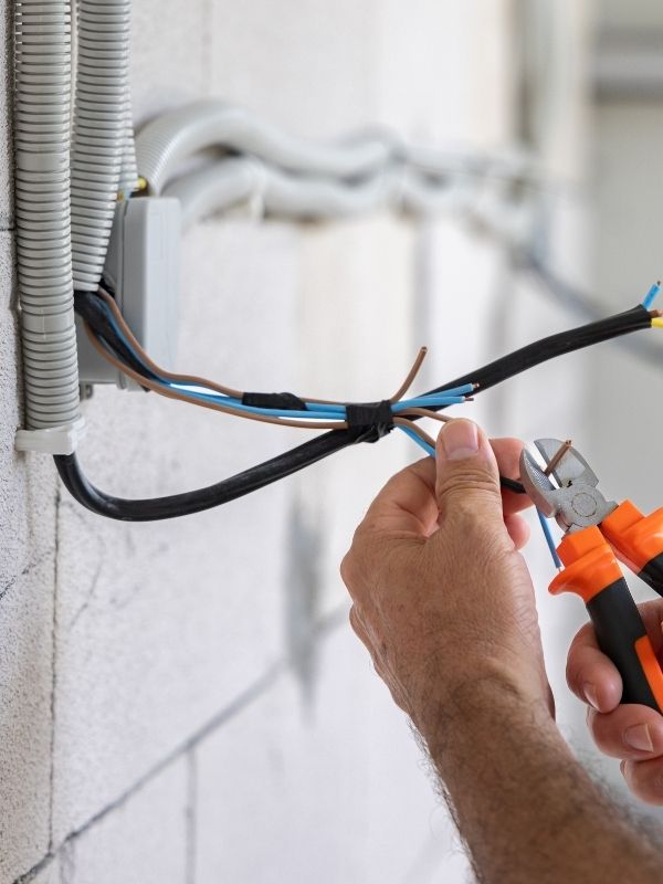 An electrician working on installing an electrical system for a new construction build. 