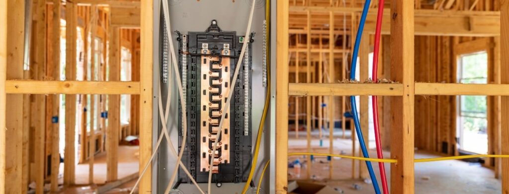 A circuit breaker box is being installed in a new construction building. 
