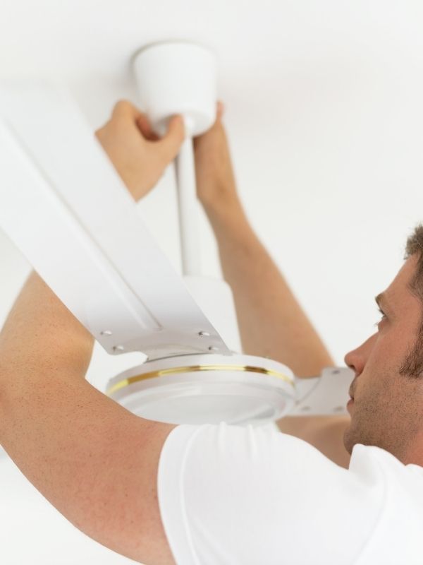 An electrician installing a ceiling fan. 
