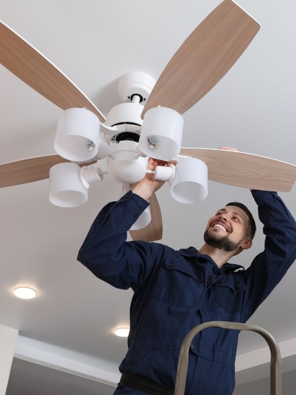 An electrician is installing a ceiling fan in a residential home. 